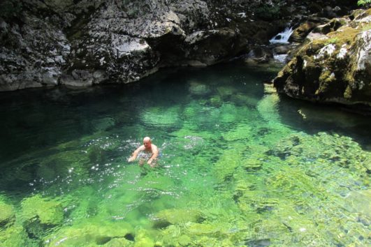 Man enjoying Multi activity holiday swimming in a crystal clear, bright blue rock pool near Lake Skadar