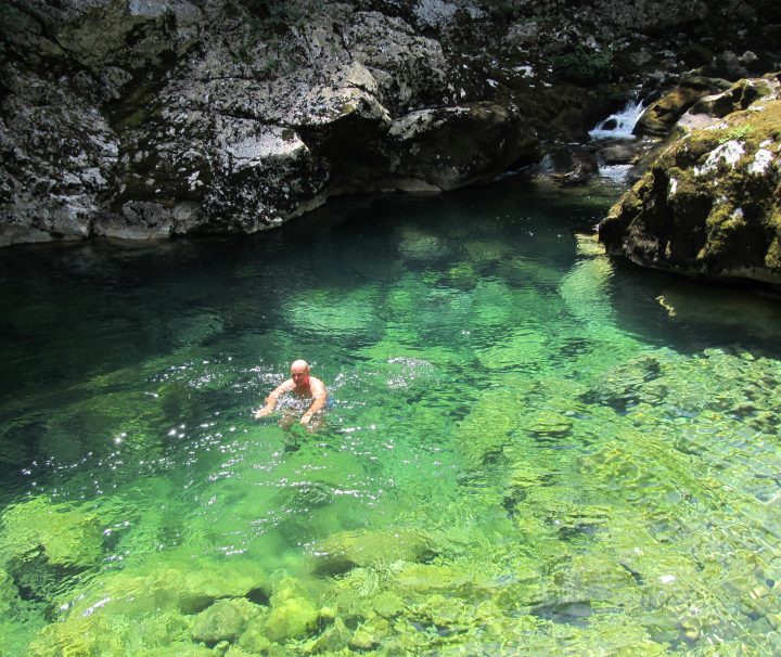 Mann auf einem Aktivitätsurlaub, der in einem kristallklaren, hellblauen Felsenbecken nahe See Skadar schwimmt