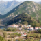 A summer view over the tiny town of Virpazar in Montenegro, next to Lake Skadar's waters, and with dried out floodplains around it and mountains above.